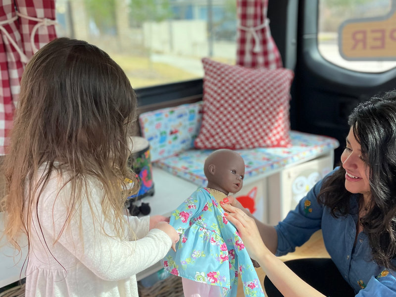 Therapist and child playing with dolls inside the van