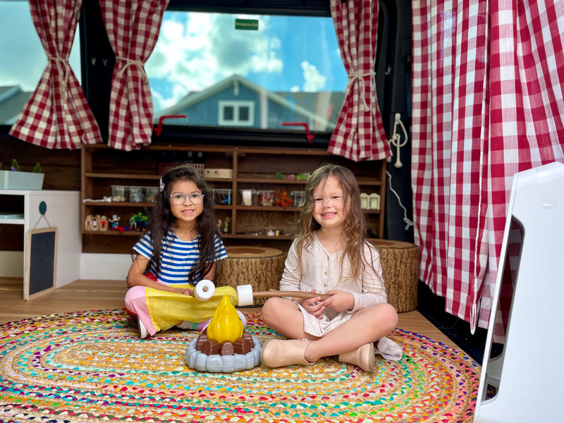 Children playing with a toy campfire on the van floor